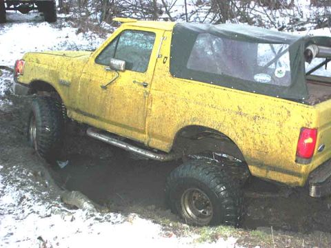 1988 Ford Bronco - Yellow Ford Bronco stuck in mud and snow, likely a 1987 model based on body style.
