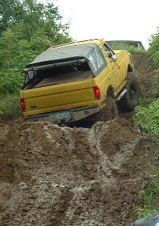 1988 Ford Bronco - 1988 Ford Bronco tackling a challenging muddy trail during an off-road excursion.