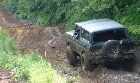 1988 Ford Bronco - A Ford Bronco navigates a challenging muddy off-road path.