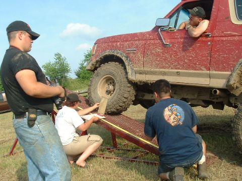 1988 Ford Bronco - Three people are measuring the tire height of a red 1988 Ford Bronco on a ramp.