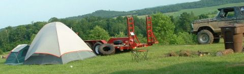 1988 Ford Bronco - Ford Bronco and trailer at a campsite with tents set up on a hill.