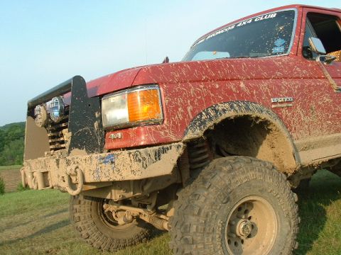 1988 Ford Bronco - This red truck, likely a 1992 Ford Bronco, is heavily covered in mud after an off-road excursion.