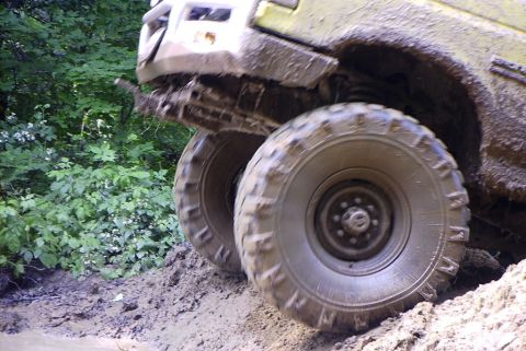 1988 Ford Bronco - This off-road vehicle navigates a challenging muddy path, its large tires gripping the slick surface.