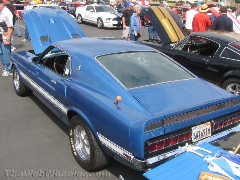 1968 Ford Mustang - A blue 1969 Shelby Mustang is displayed with its hood open, alongside other vehicles at an outdoor car show.