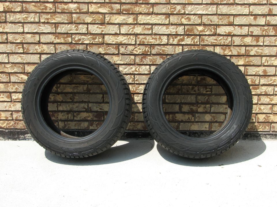 Two black tires against a brick wall