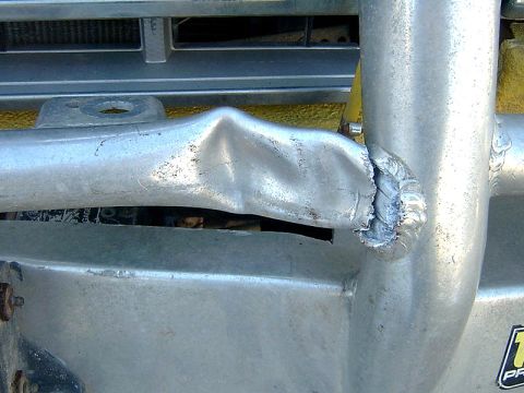 1988 Ford Bronco - Damaged metal bumper guard shows signs of impact and repair.