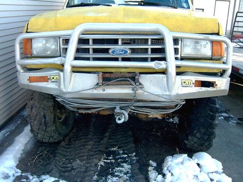 1988 Ford Bronco - This Ford truck features a large brush guard and winch, with knobby tires suitable for off-road conditions.