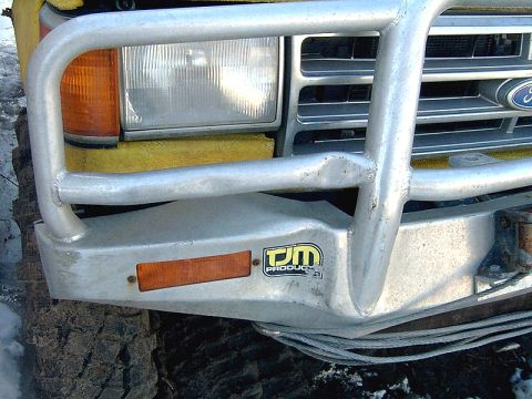 1988 Ford Bronco - Front view of a yellow 1988 Ford Bronco, equipped with a heavy-duty brush guard and a 'DM PRODUCTS' decal.