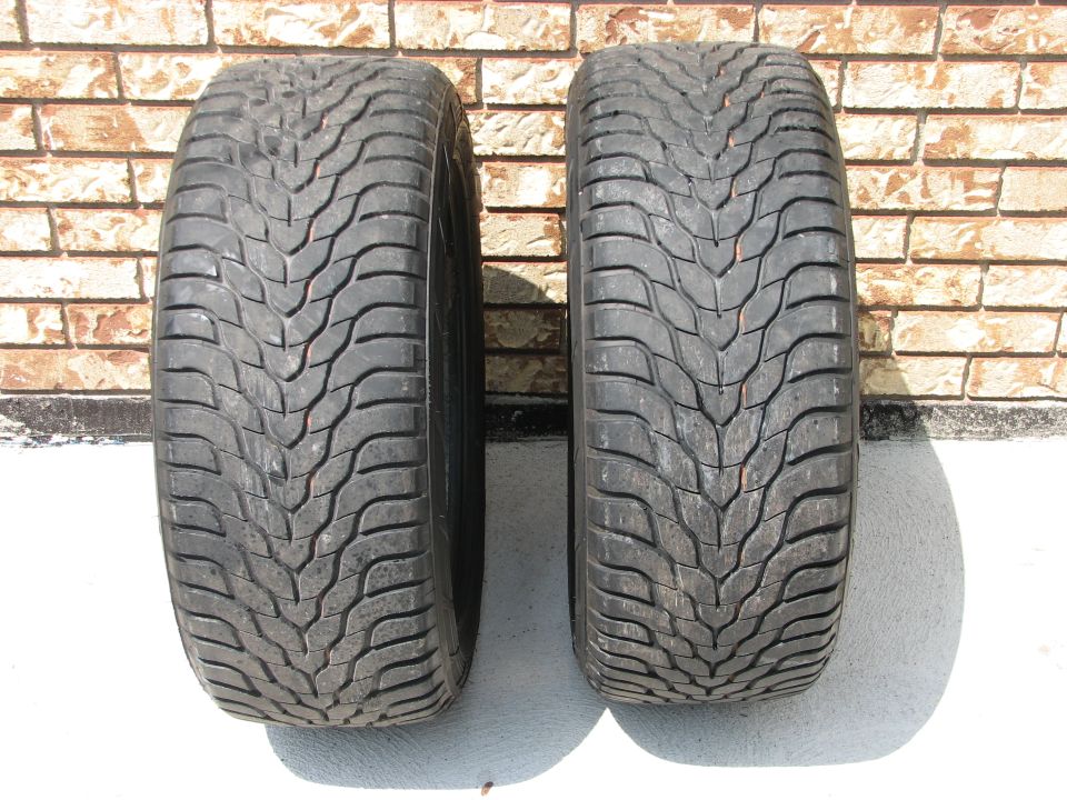 Two tires with V-shaped tread pattern against a brick wall