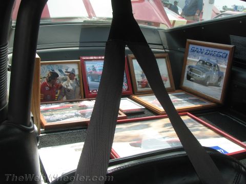 1968 Ford Mustang - A collection of framed photographs, including racing scenes and portraits, are arranged inside a car's interior.
