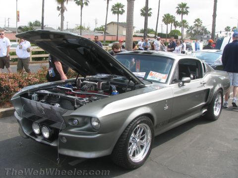 1968 Ford Mustang - A gray 1967 Shelby GT500 is displayed with its hood open, revealing the engine and shiny chrome wheels.