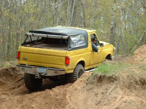 1988 Ford Bronco - This 1988 Ford Bronco is shown off-roading on a dirt path, demonstrating its capability on challenging terrain.
