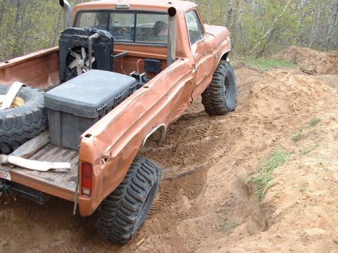 1988 Ford Bronco - This pickup truck is equipped with large off-road tires and appears to be navigating a challenging dirt terrain.