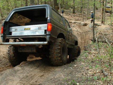 1988 Ford Bronco - This modified 1988 Ford Bronco navigates a challenging off-road trail with its large tires and lifted suspension.