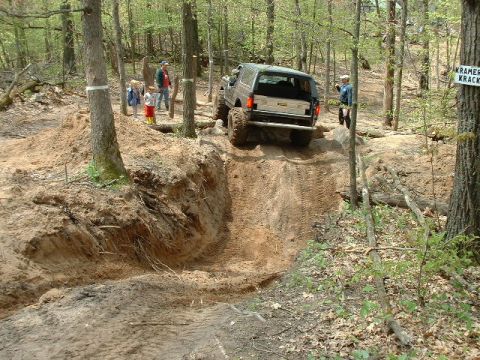 1988 Ford Bronco - An SUV navigates a challenging off-road trail with onlookers present.
