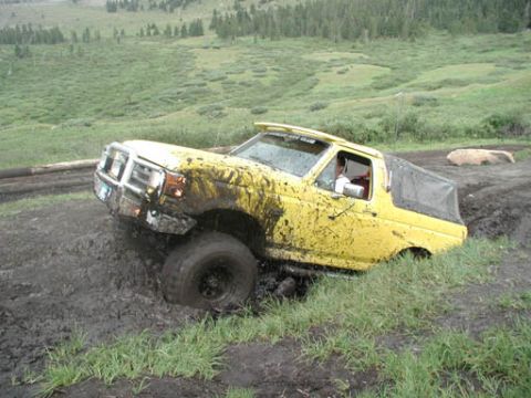 1988 Ford Bronco - This yellow off-road vehicle appears to be stuck in the mud during an off-road excursion.