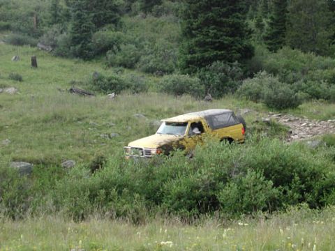 1988 Ford Bronco - 1988 Ford Bronco navigating an off-road trail surrounded by natural landscape.