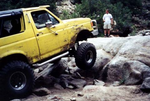 1988 Ford Bronco - This modified SUV is navigating a rocky trail, its off-road capabilities.