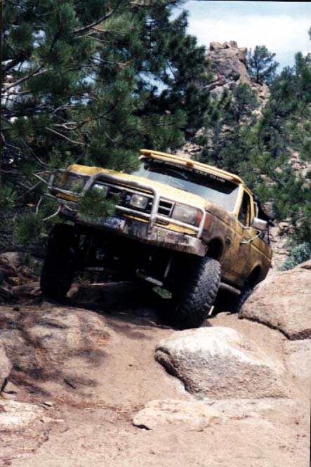 1988 Ford Bronco - This yellow truck, likely a 1987 model, is shown off-roading on a dirt and rock path.