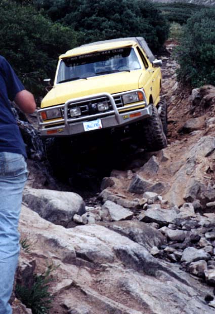 1988 Ford Bronco - A 1988 Ford Bronco tackles a challenging off-road course with large rocks and steep inclines.