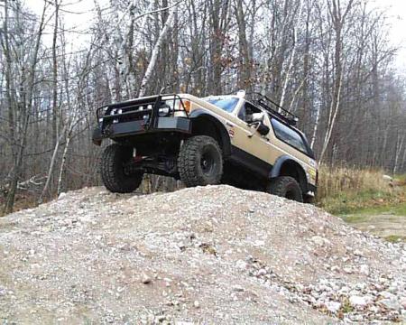 1988 Ford Bronco - This 1988 Ford Bronco is shown off-road, navigating a steep dirt incline with its large tires.