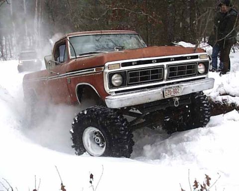 1988 Ford Bronco - A lifted 1977 Ford pickup truck navigates a snowy trail, kicking up snow.