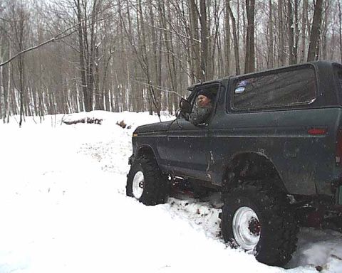 1988 Ford Bronco - A dark green Ford Bronco navigates a snowy, wooded area.