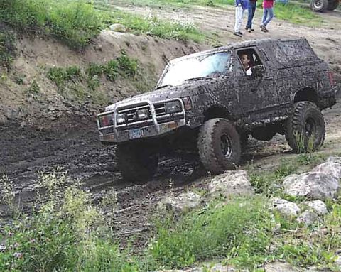 1988 Ford Bronco - A heavily mud-covered 1987 Ford Bronco navigates a muddy off-road course.