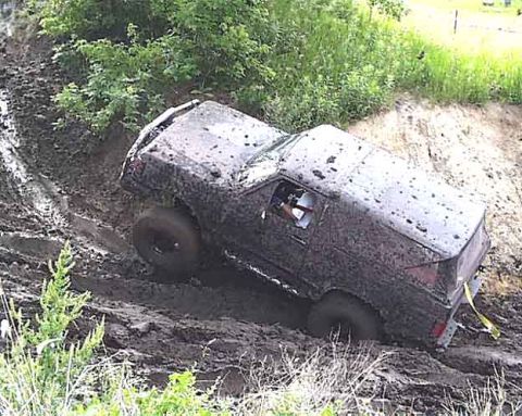 1988 Ford Bronco - An SUV is stuck in thick mud on an off-road trail.