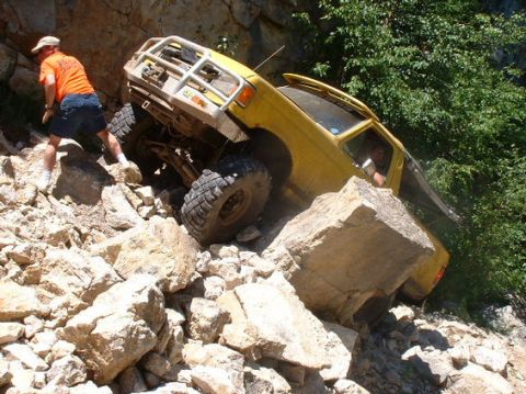 1988 Ford Bronco - 1988 Ford Bronco tackling a difficult rocky trail with a person guiding.