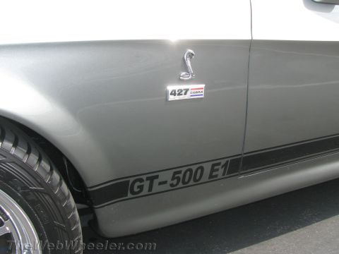 1968 Ford Mustang - A close-up view of the side of a silver 1968 Ford Mustang GT-500 E1, showing its distinctive badging and stripes.