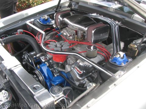 1968 Ford Mustang - The engine bay of a 1968 Ford Mustang features a polished intake, dual carburetors, and a chrome strut tower brace.