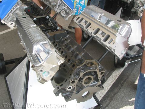 1968 Ford Mustang - Multiple engine components, including valve covers and engine blocks, are displayed on stands at an outdoor event.