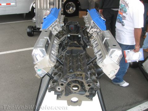 1968 Ford Mustang - A V8 engine block is displayed with chrome valve covers and blue intake manifolds, suggesting a performance build.
