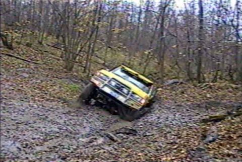 1988 Ford Bronco - 1988 Ford Bronco navigates a challenging muddy incline during an off-road excursion.