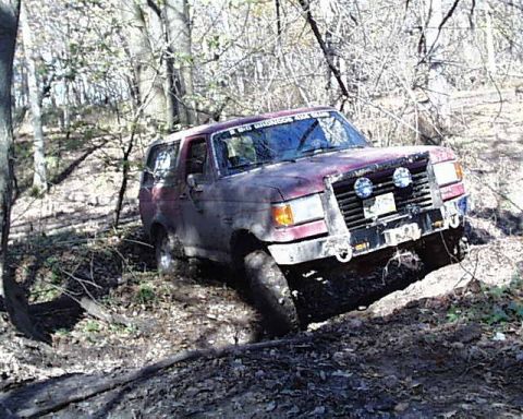 1988 Ford Bronco - This off-road SUV appears to be stuck in a muddy trail, with its front end angled downwards.