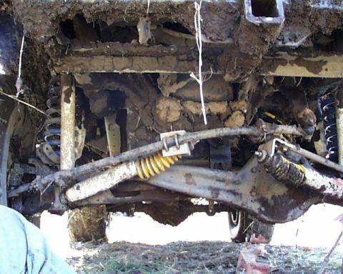 1988 Ford Bronco - The heavily soiled undercarriage of a vehicle is visible, obscuring specific details.