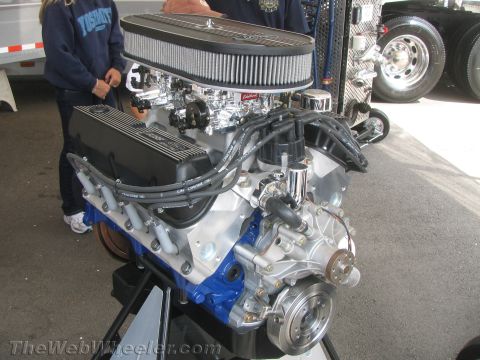 1968 Ford Mustang - A Ford V8 engine is displayed on a stand, with a large air filter and chrome components visible.