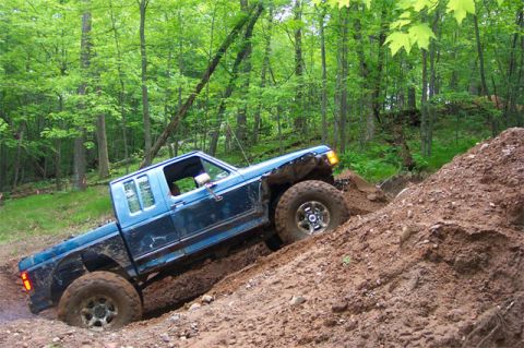 1988 Ford F-250 - Pickup truck navigating a steep, muddy incline during an off-road excursion.