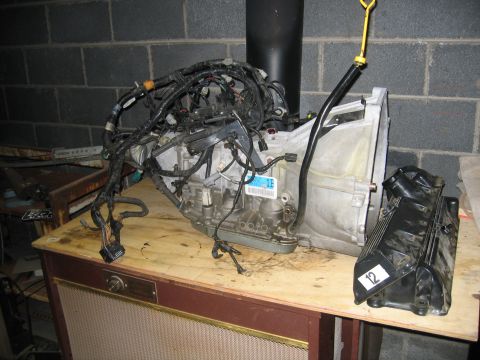 1996 Ford Crown Victoria - Transmission and engine components are laid out on a wooden surface against a brick wall.