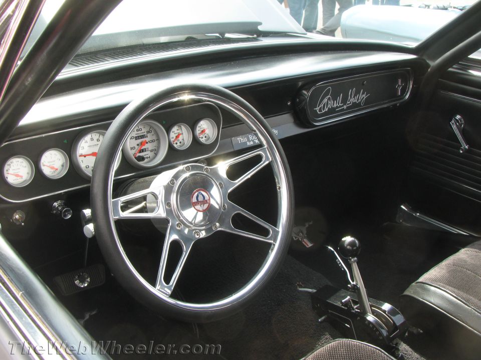 Interior view of a 1965 Shelby Mustang with Carroll Shelby's signature on the dash and custom gauges