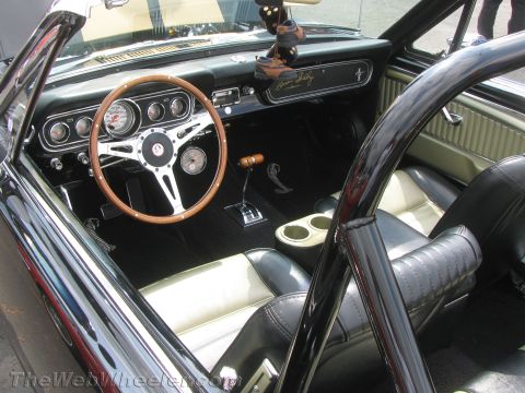 1968 Ford Mustang - The interior of a classic Ford Mustang convertible features a roll bar and distinctive Shelby Cobra badging on the dashboard.
