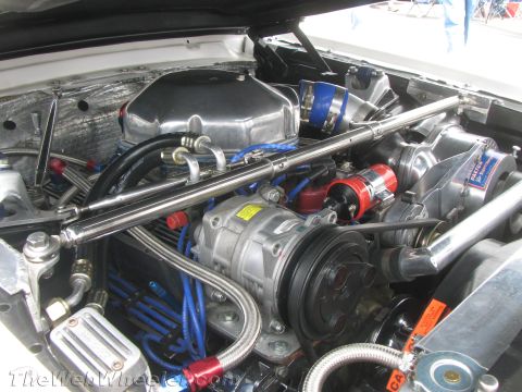 1968 Ford Mustang - Close-up view of a highly modified engine bay a polished supercharger and extensive chrome detailing.