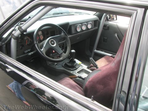 1968 Ford Mustang - The interior of a modified car features racing seats, a roll cage, and auxiliary gauges mounted on the dashboard.