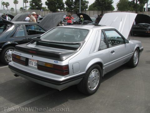 1968 Ford Mustang - This silver Ford Mustang hatchback is parked at an outdoor car show with its hood open.
