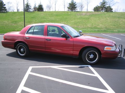 2001 Ford Crown Victoria - Side view of a red 2001 Ford Crown Victoria parked in a lot.