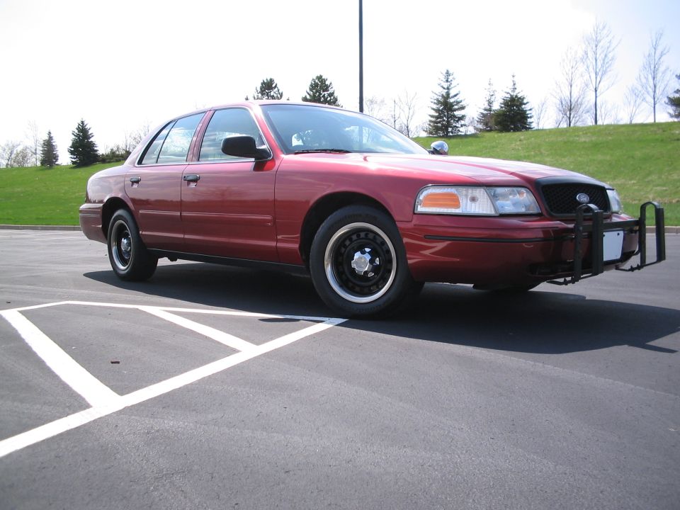 Red 2001 Ford Crown Victoria with a push bumper parked on asphalt