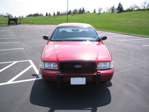 2001 Ford Crown Victoria - Front view of a red 2001 Ford Crown Victoria, equipped with a push bumper, in a parking lot.