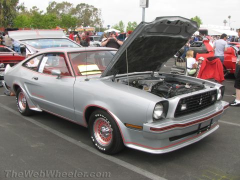 1968 Ford Mustang - A silver Ford Mustang II with red accents and its hood open is parked at an outdoor event.