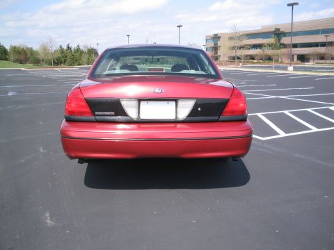 2001 Ford Crown Victoria - The rear of a red Ford Crown Victoria is shown in a parking lot with an office building in the background.